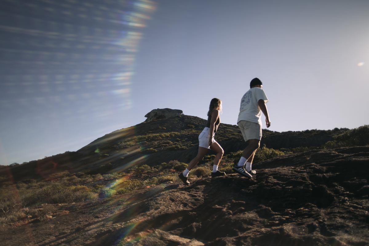 Two people walking up a small rocky hill. 