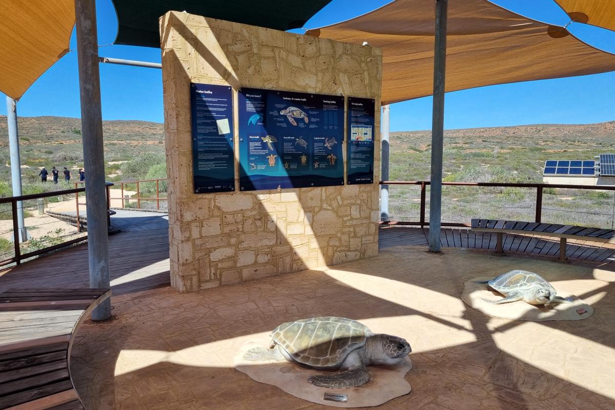 Shaded area with limestone wall and information panels. 