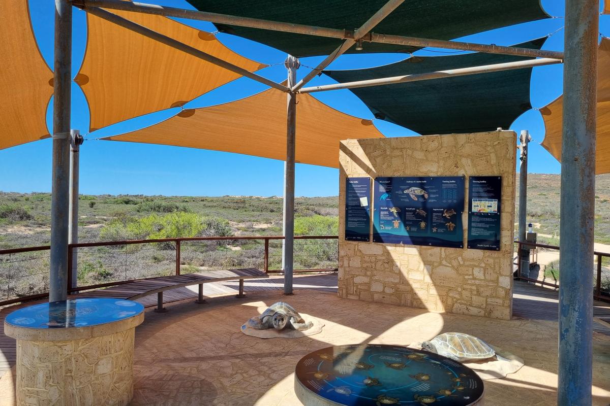 Shaded area with limestone wall and information panels. 