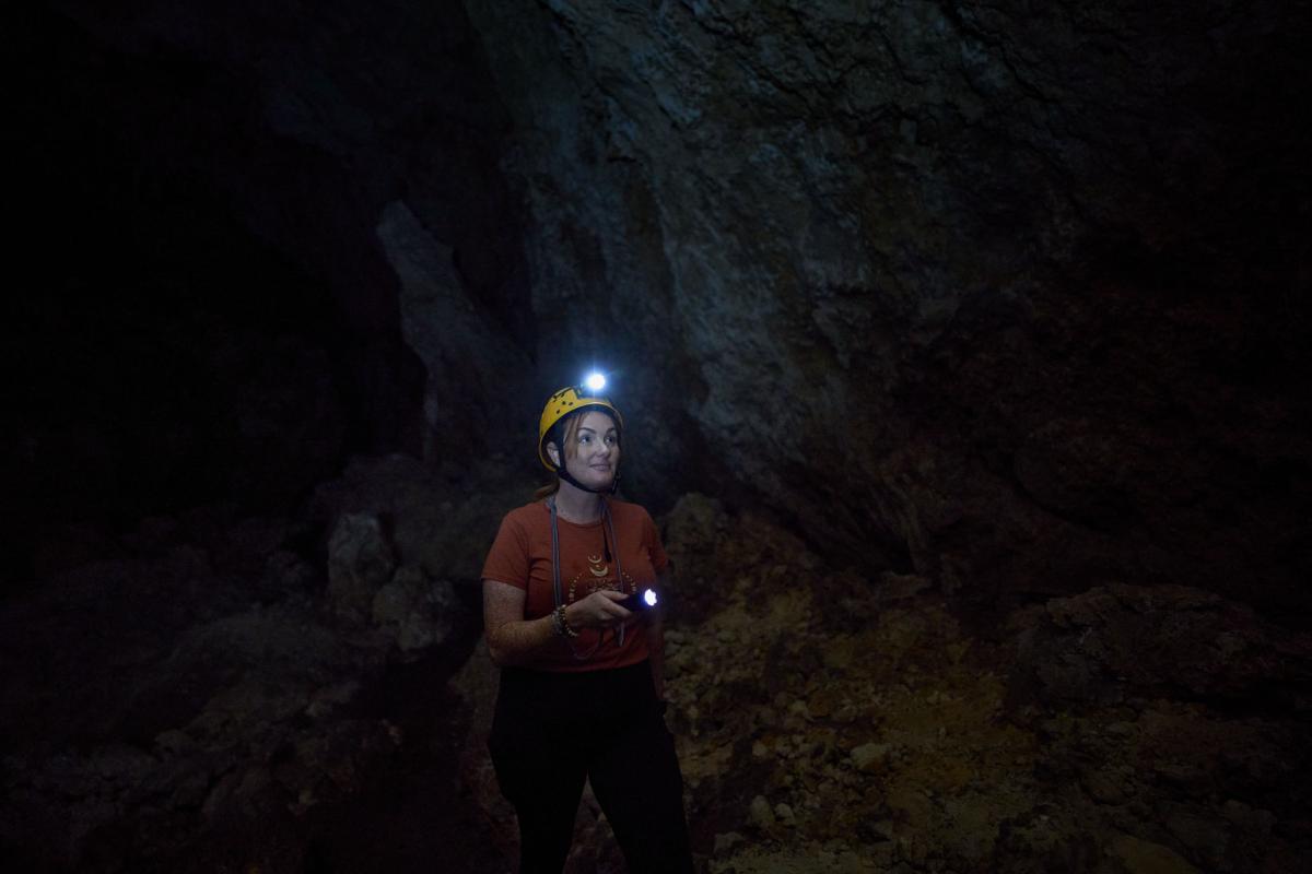Woman pointing torch inside Giants Cave