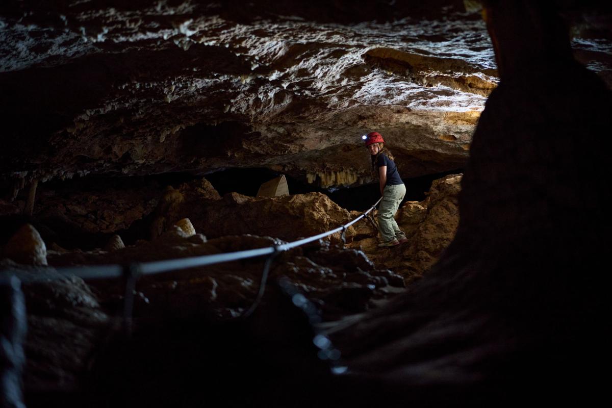 Girl walking down slope using rope in Giants Cave