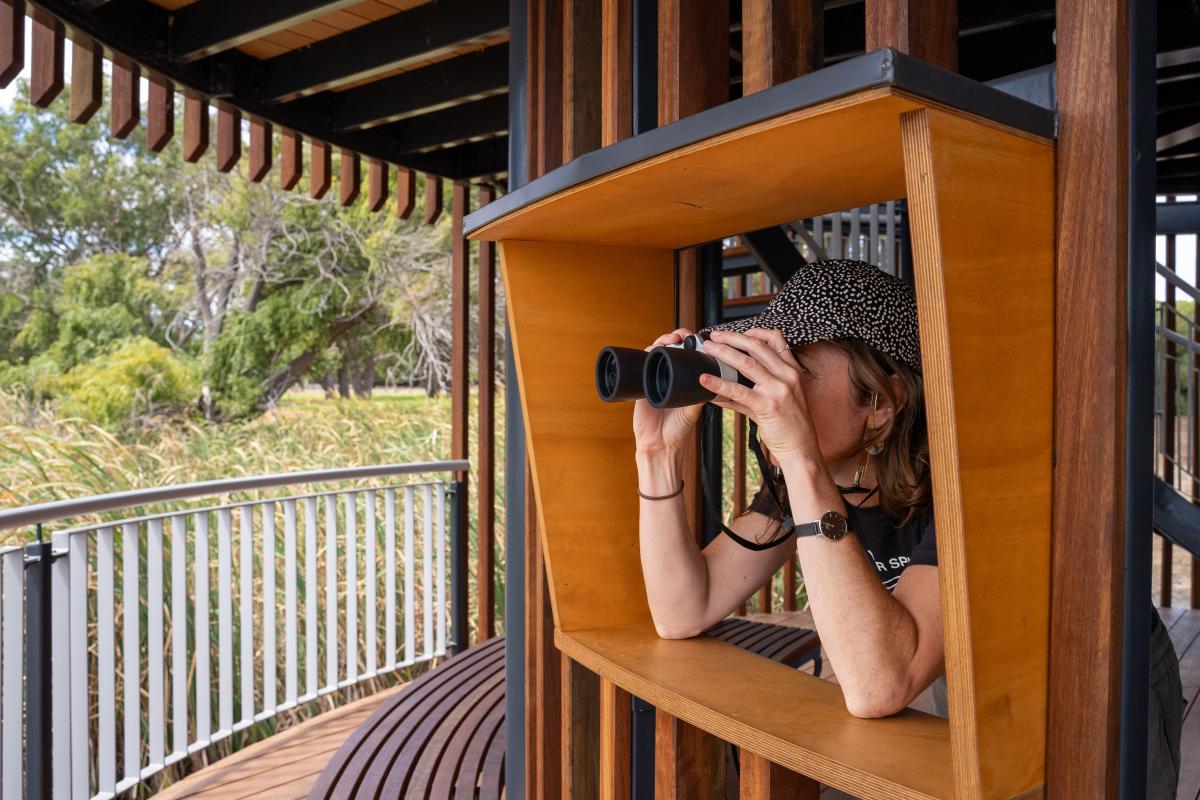 Person looking through a window with binoculars. 