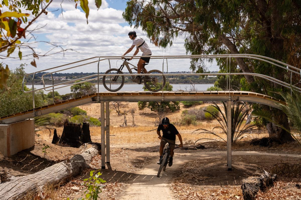 Person riding over bridge on mountain bike trails. 