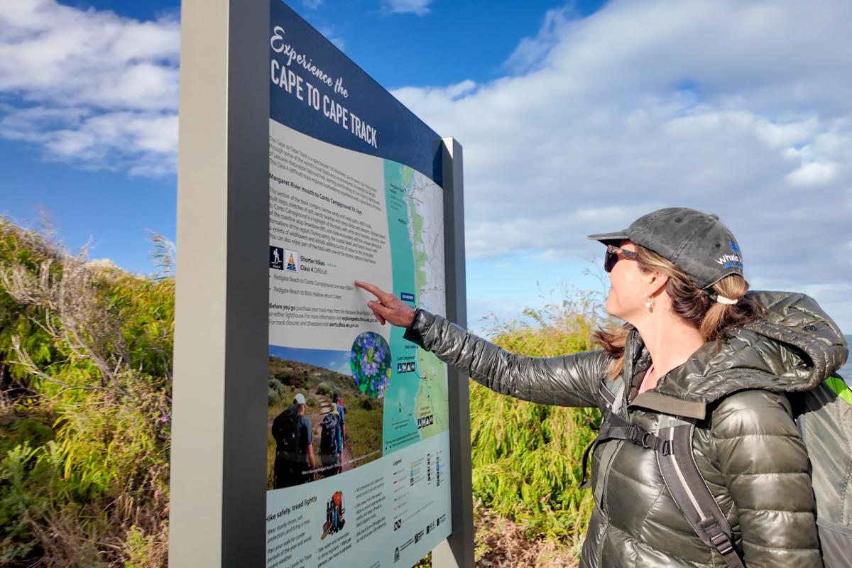 Person reading a sign on a walk trail. 