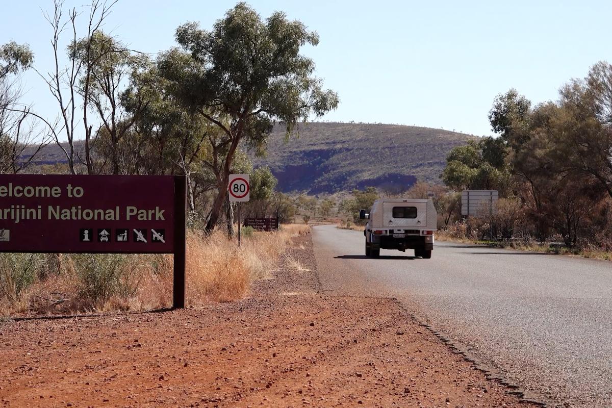 Car on a road passing a Karijini National Park sign