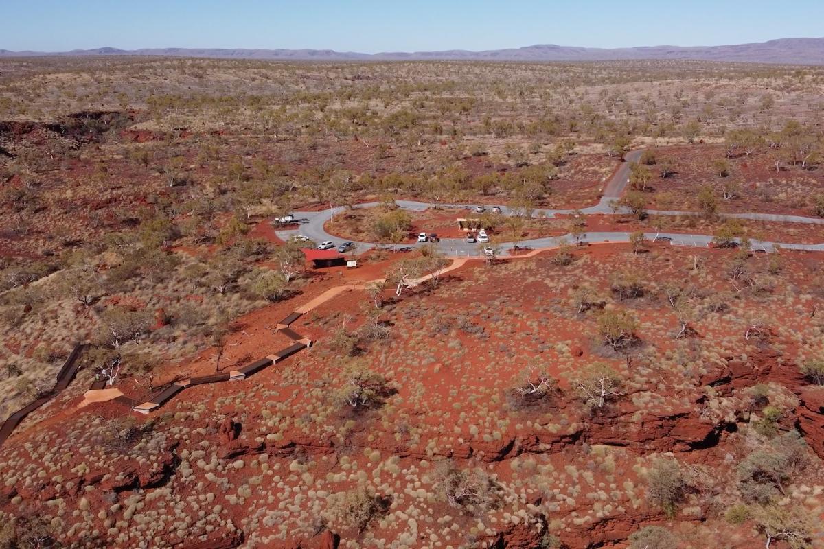 Aerial view lookig down onto a new car park surrounded by red dirt and low shrubs. 