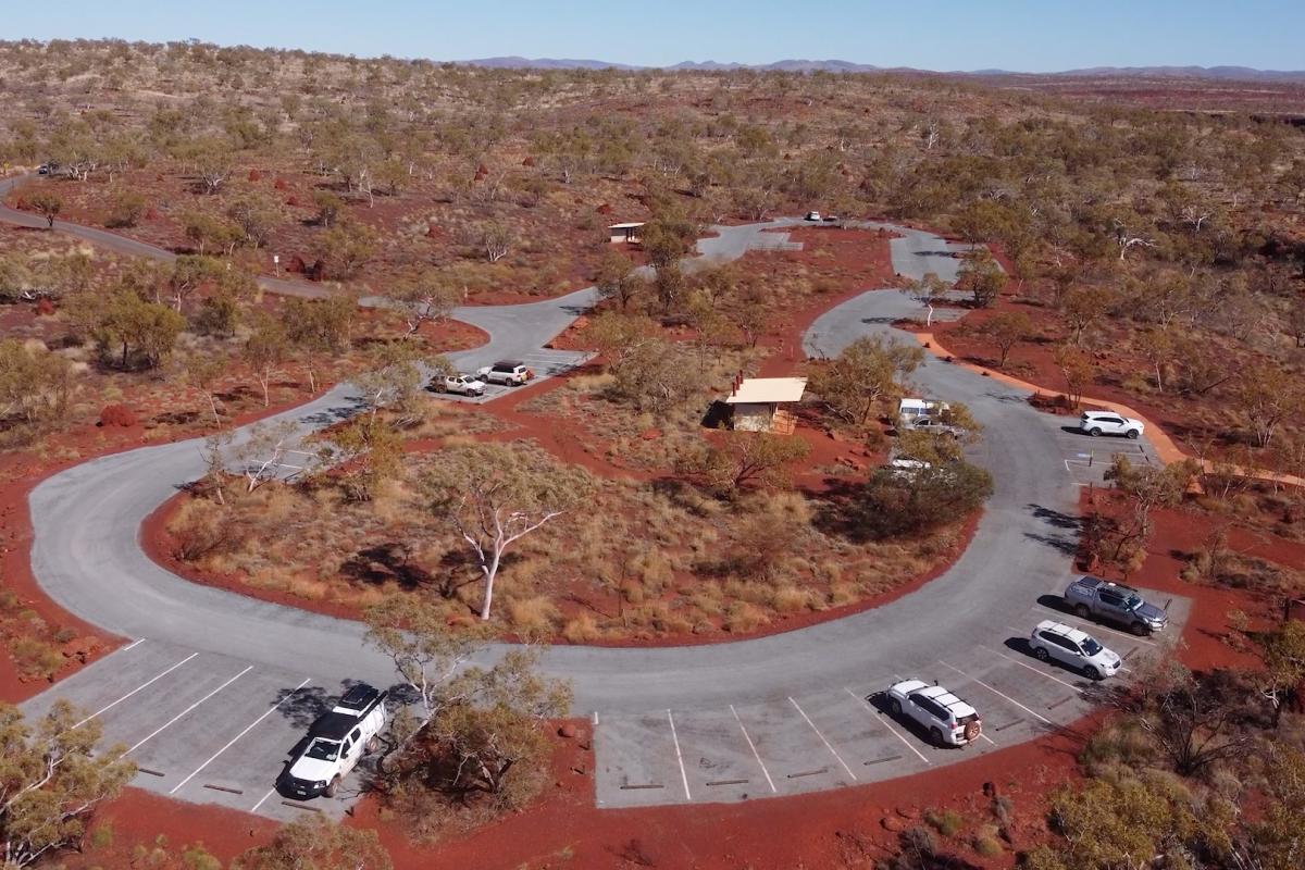 Aerial view of a car park surrounded by red dirt and low shrubs.