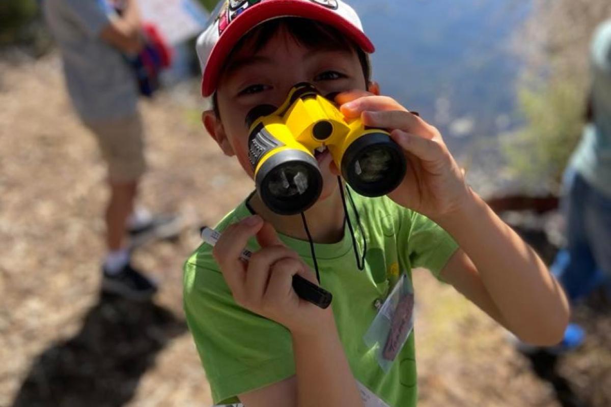 Close up of child with binoculars near the river.