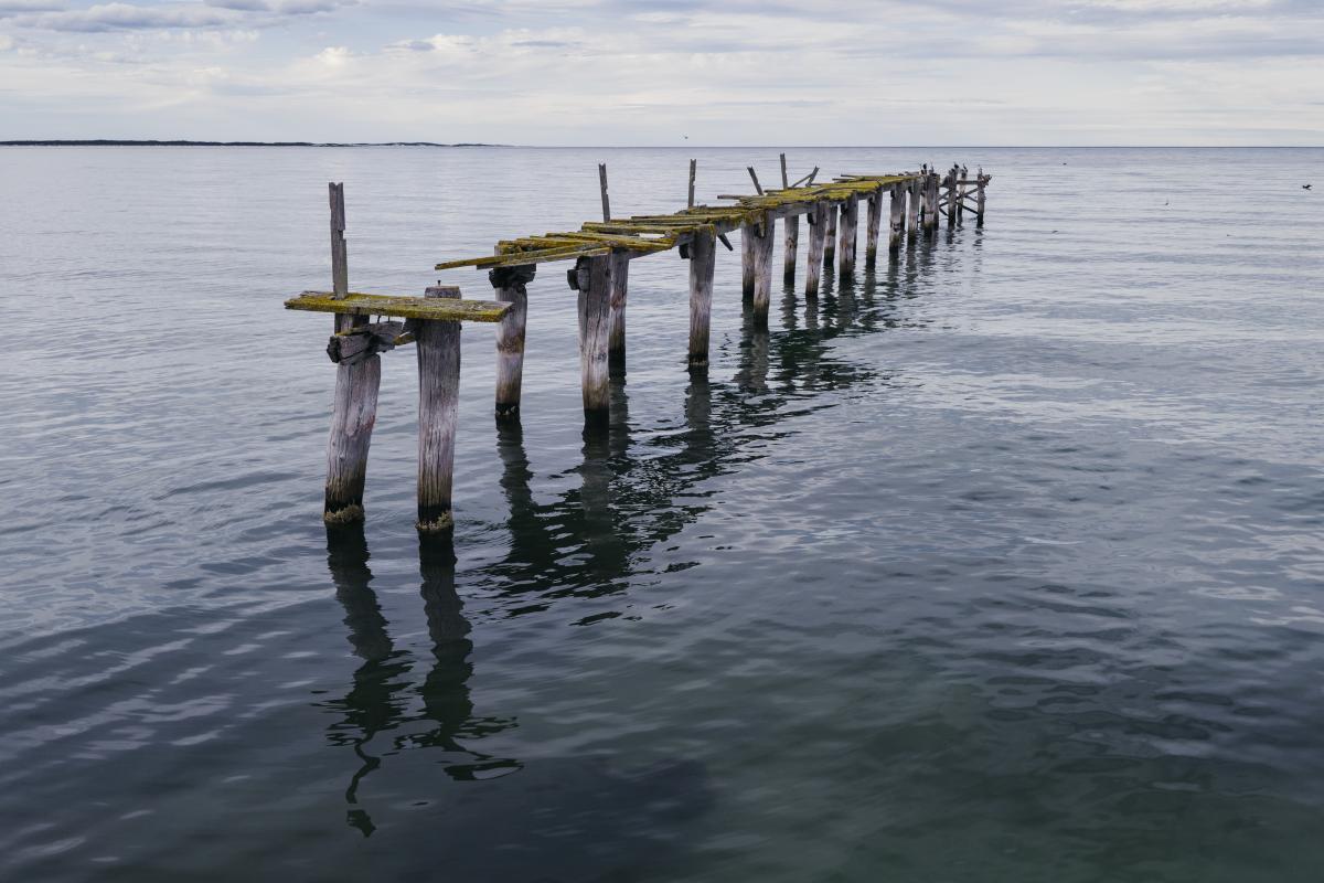 Ruined wood jetty in water.